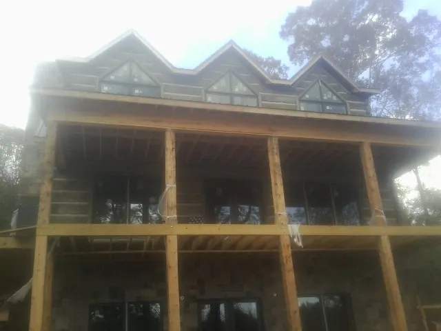 Dormers and porch framing on a large log home under construction — Roof Coating work by our crew in Roxbury
