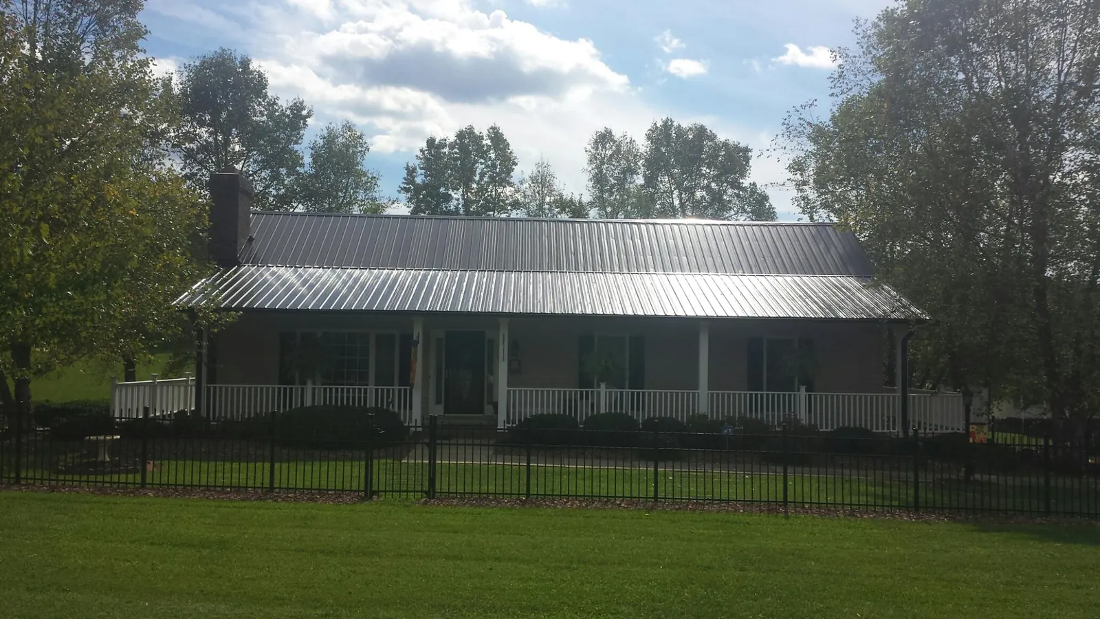Gray metal roof on a brick ranch with a full width front porch — Gutter Guard Installation work by our crew in Roxbury