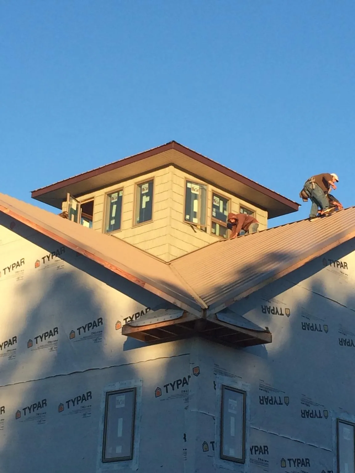 Roofers working around a rooftop cupola on a new metal roof at sunset — Roof Waterproofing in Roxbury by Roofing Brothers